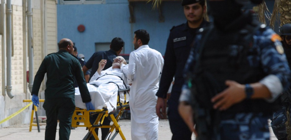 Kuwaiti emergency personnel pull a man on stretchers past security forces outside the Shiite Al-Imam al-Sadeq mosque after it was targeted by a suicide bombing during Friday prayers on June 26, 2015, in Kuwait City. The Islamic State group-affiliated group in Saudi Arabia, calling itself Najd Province, said militant Abu Suleiman al-Muwahhid carried out the attack, which it claimed was spreading Shiite teachings among Sunni Muslims. AFP PHOTO / STR